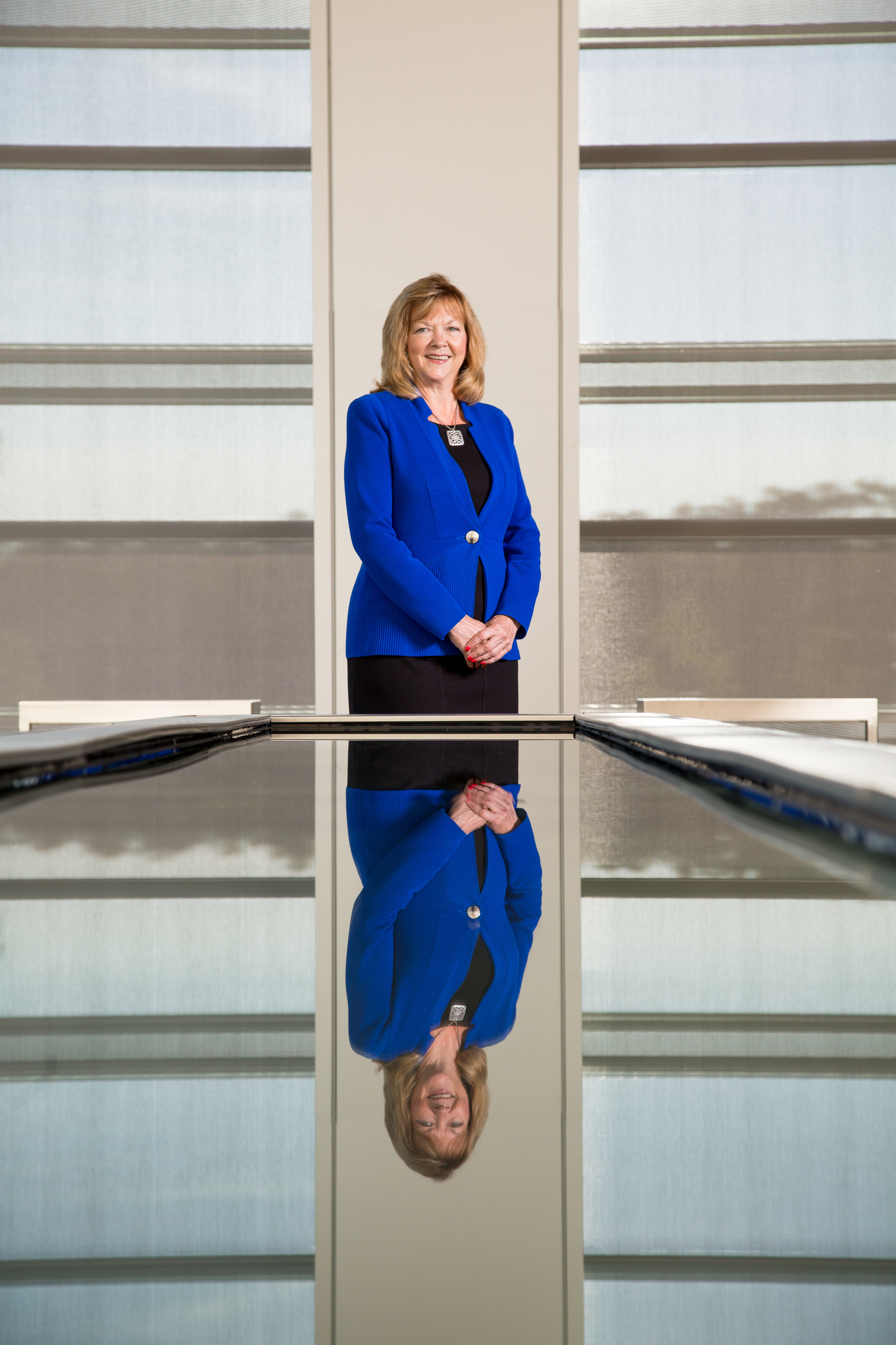 Sara Ortwein, President of ExxonMobil Upstream Research Company (URC) at the ExxonMobil campus, standing at far end of reflective table