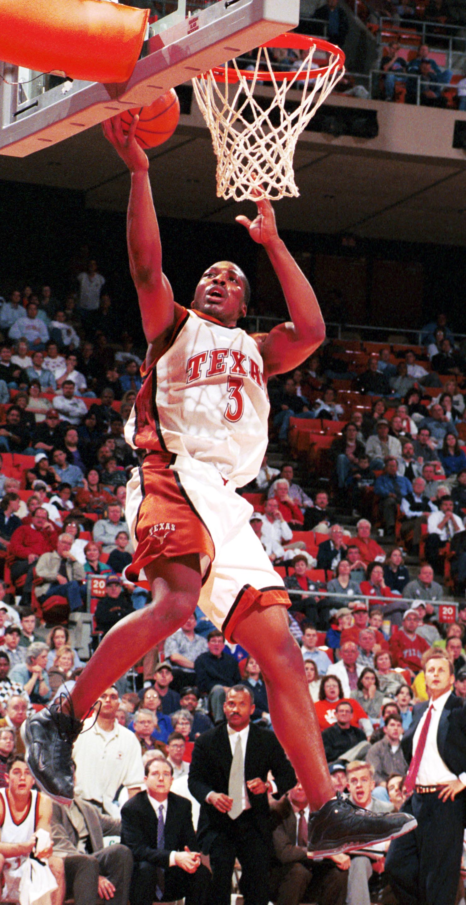 Muoneke jumps up to make a layup at a UT basketball game, crowd in the background