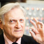 Texas Engineer John B. Goodenough holding a lithium-ion battery