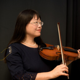 Emma Fan holds violin with sensor attached to her arm