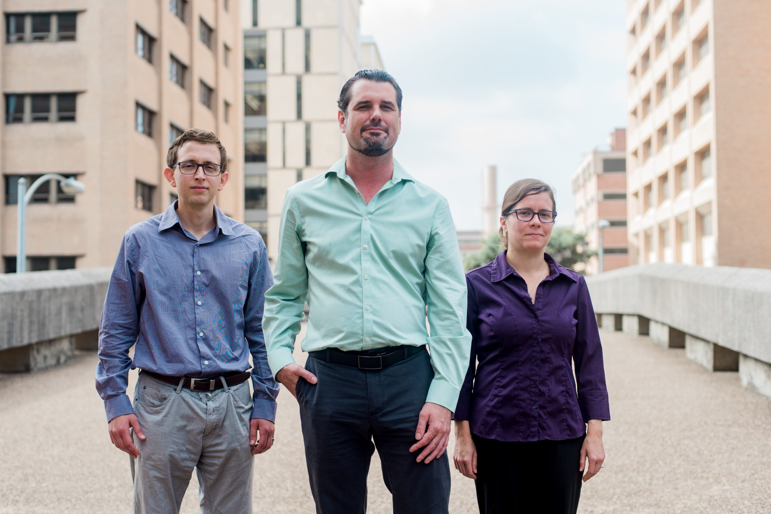 Ryan Jadrich, Tom Truskett, and Beth Lindquist pose side by side, outside with academic buildings in background