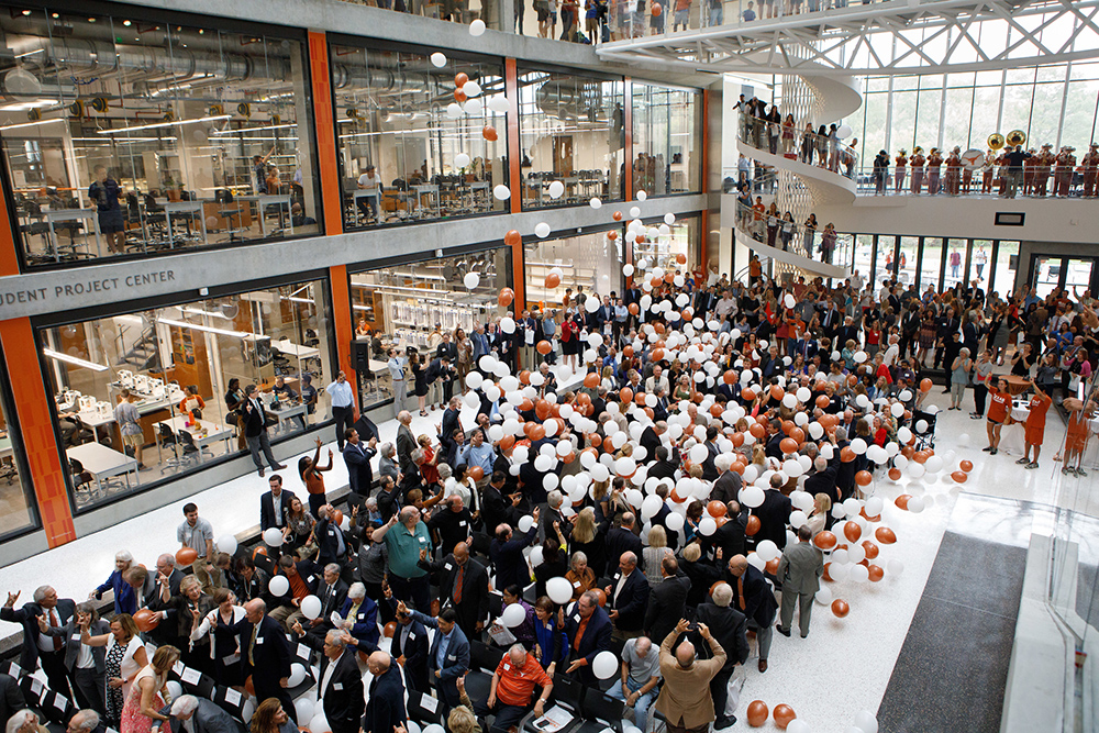 Orange and white balloons fall on a crowd in the EERC atrium