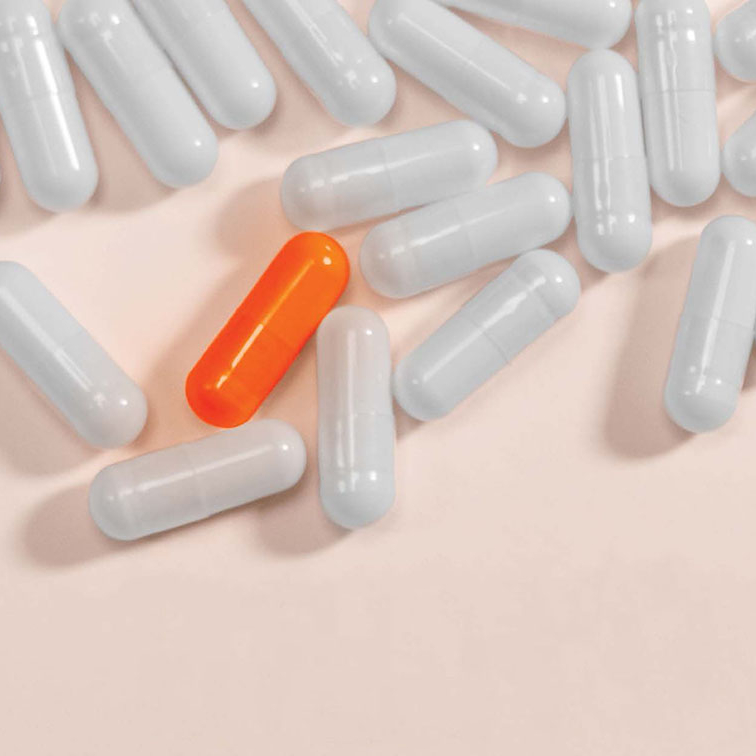 stock image of white pills with one orange pill