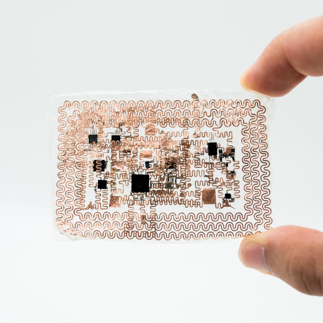 Fingers holding up e-tattoo prototype