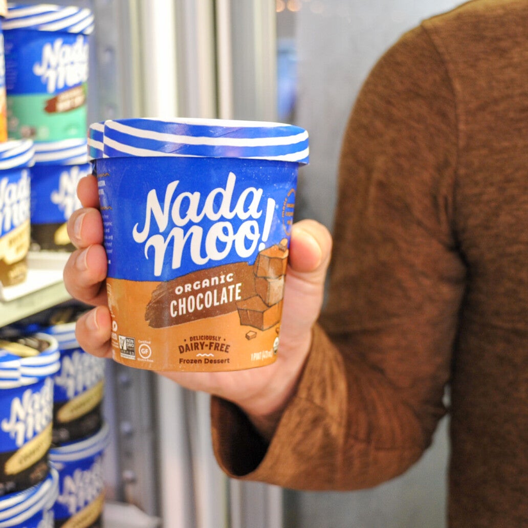 Nada moo! pint of dairy free ice cream in front of fridge display of Nada moo! pints