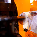 Texas Engineer researcher dressed in lab gear working on machine