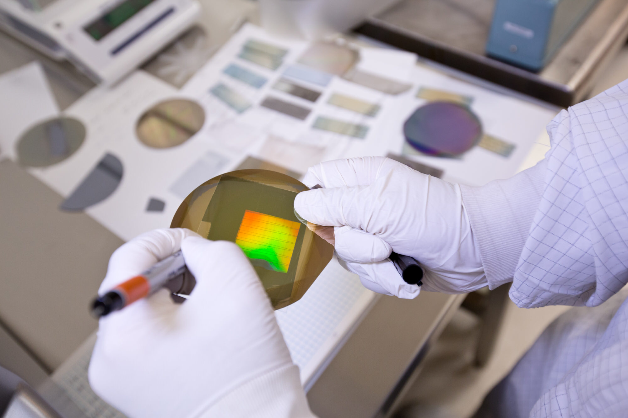 Gloved hands holding microchip materials above a table