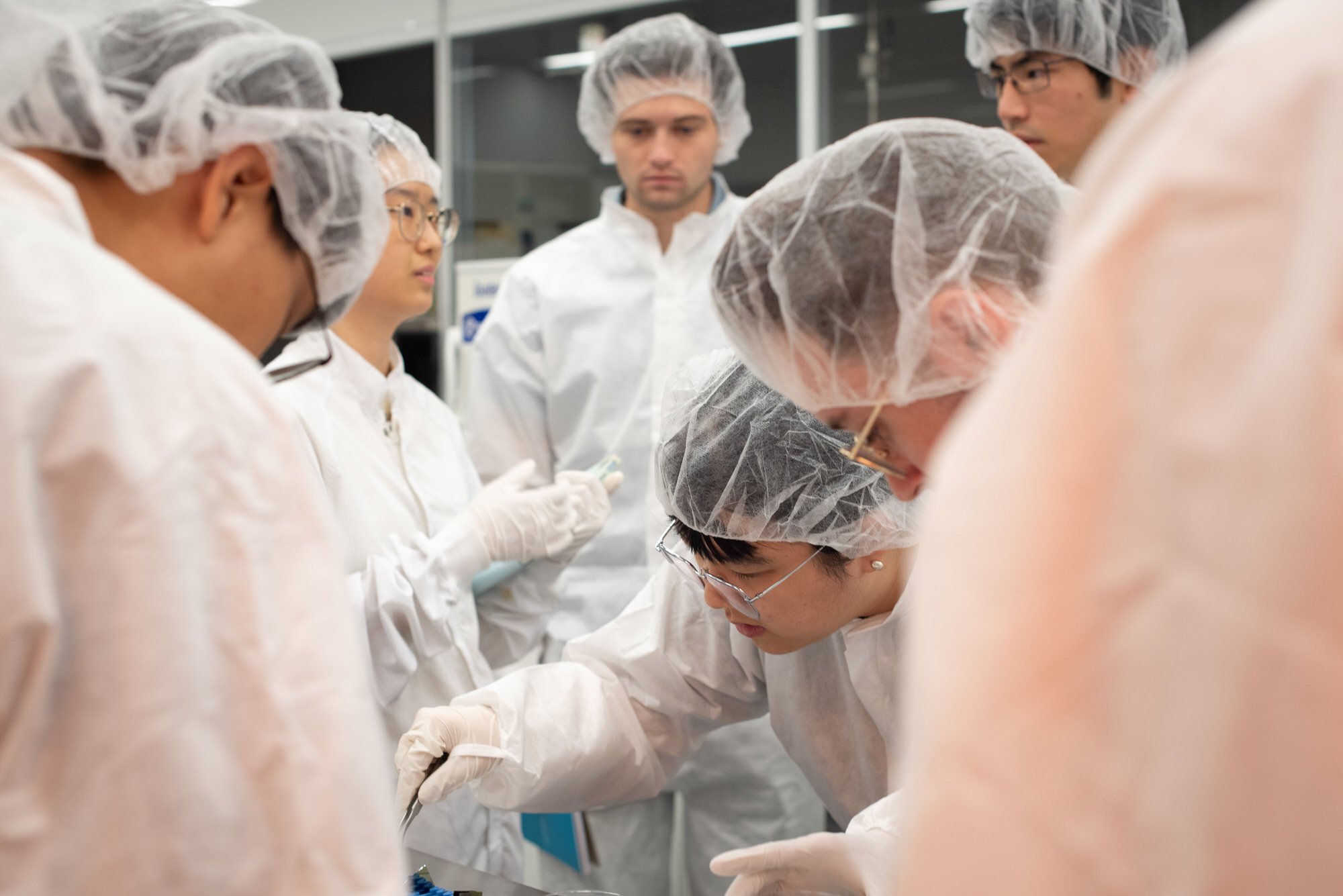 Texas Engineers wearing lab gear looking closely at semiconductor research material