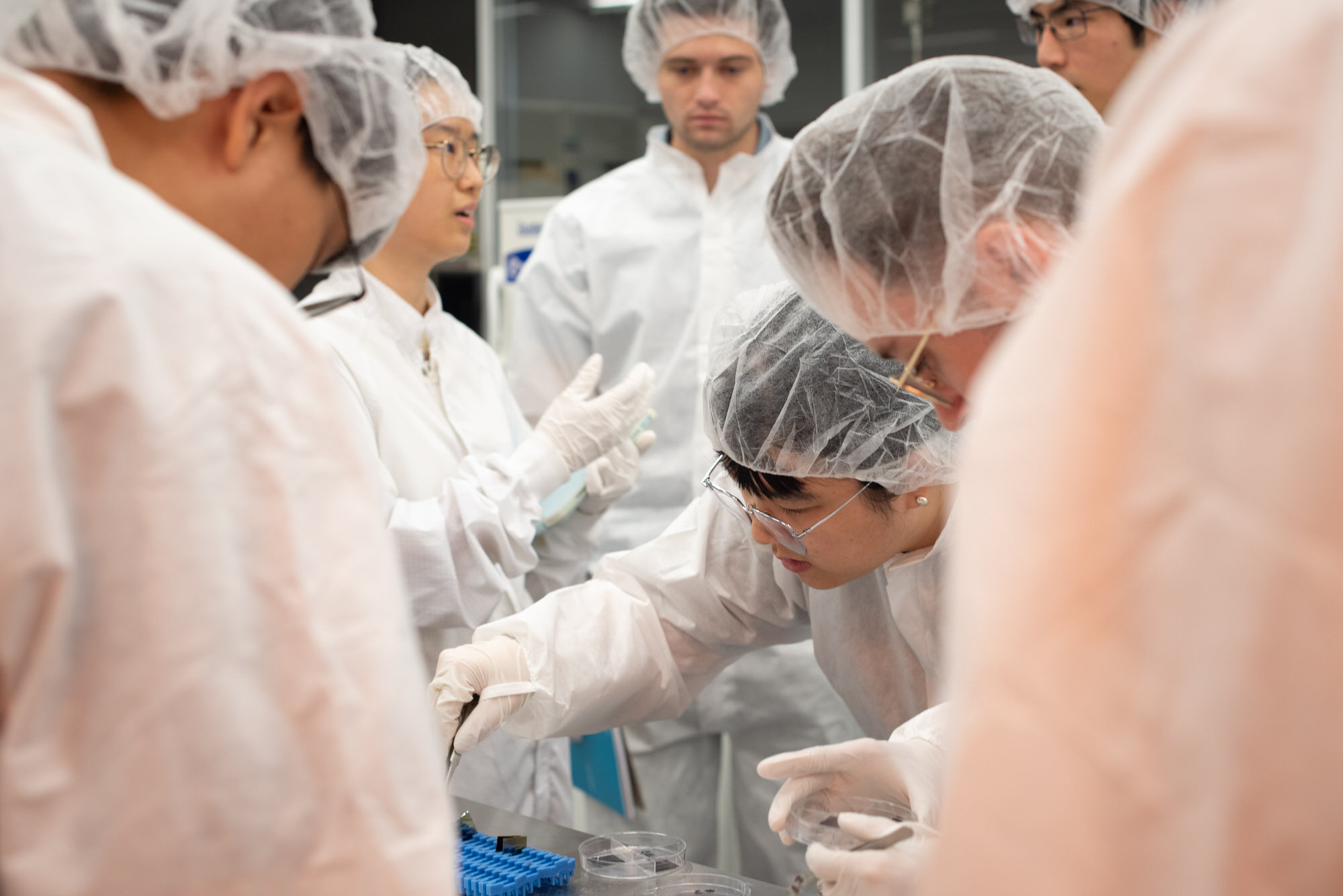 Texas Engineers wearing lab gear looking closely at semiconductor research material