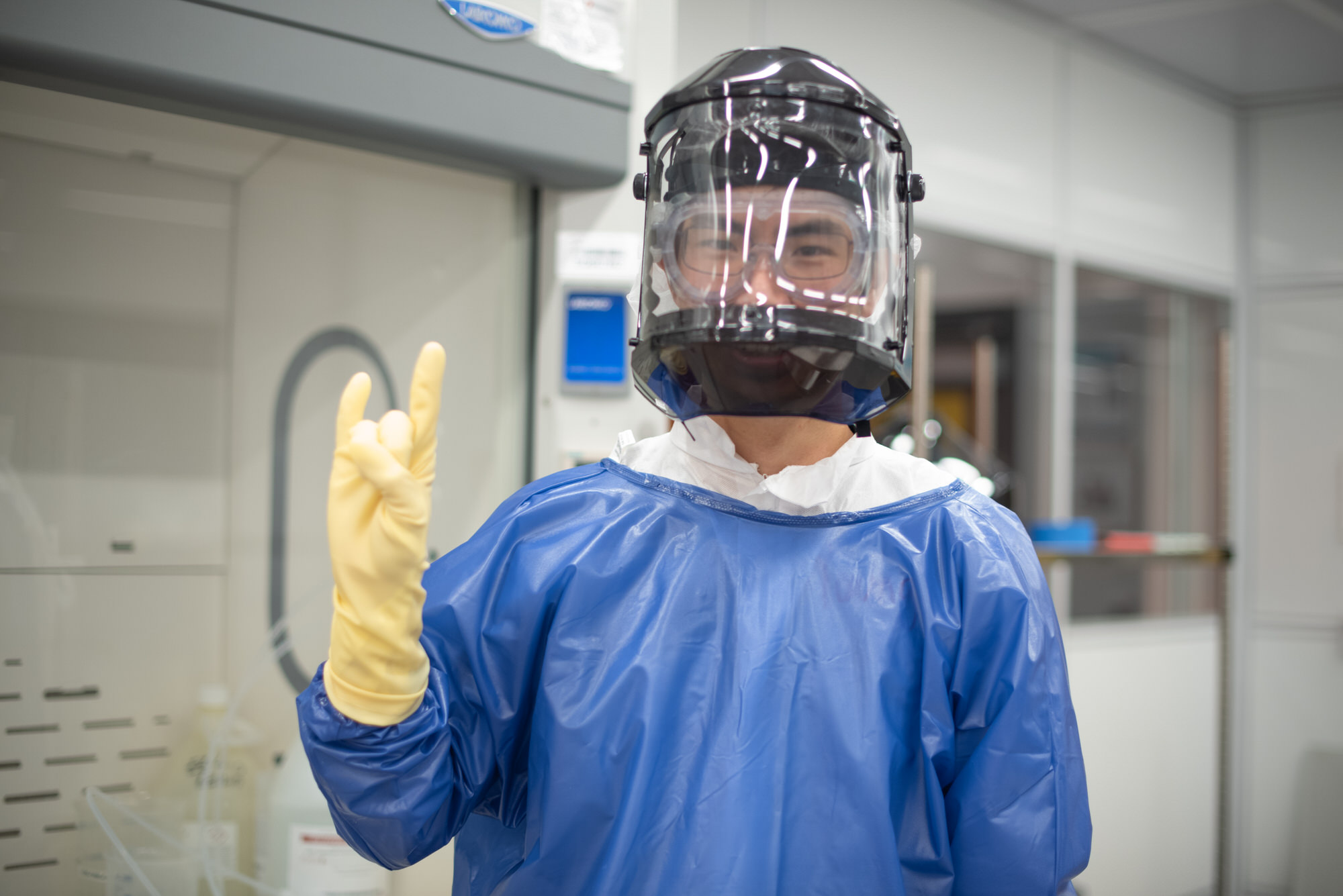 Texas Engineer in lab gear doing hook 'em horns hand sign with gloved hand