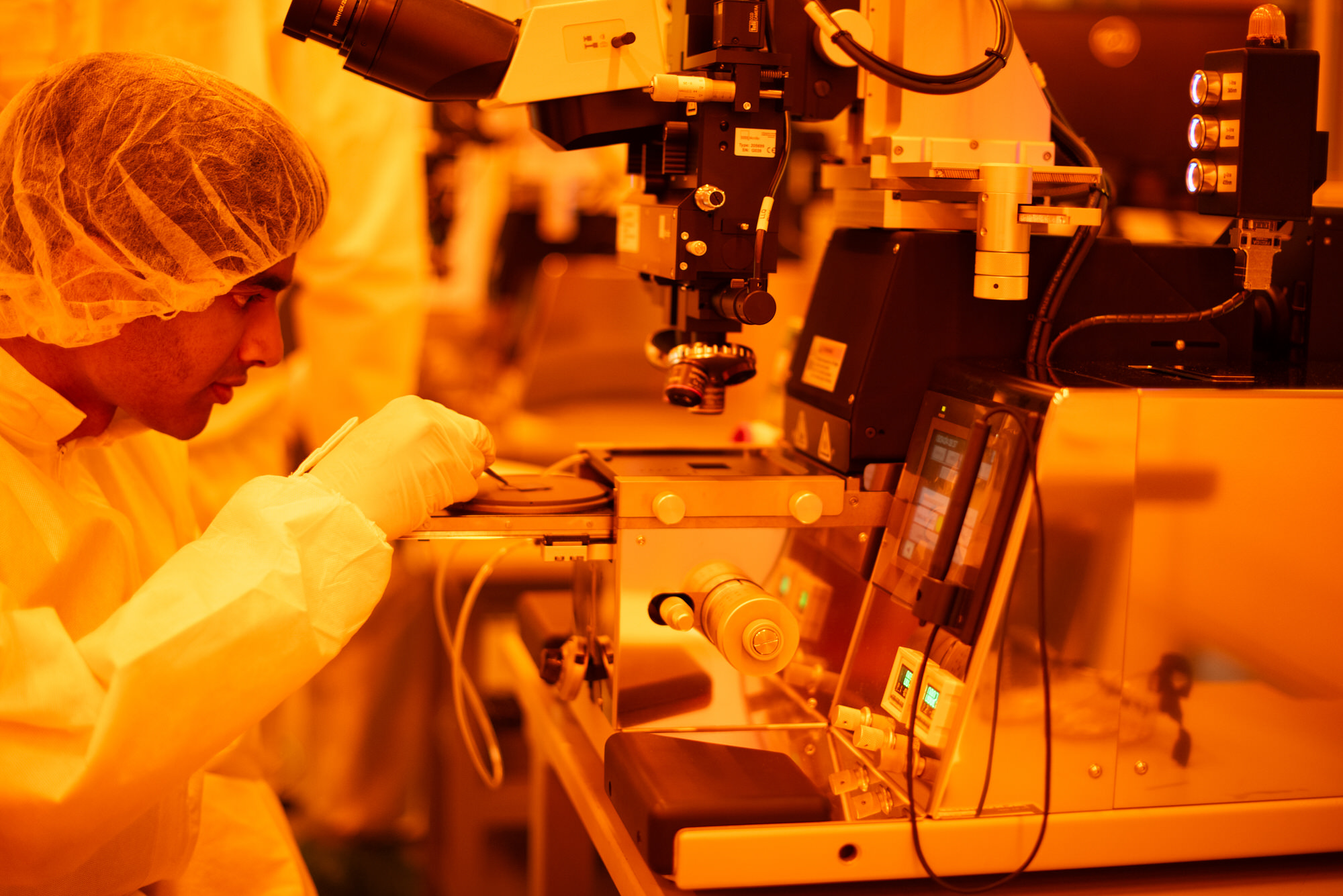 Texas Engineer in lab gear working with a large microscope