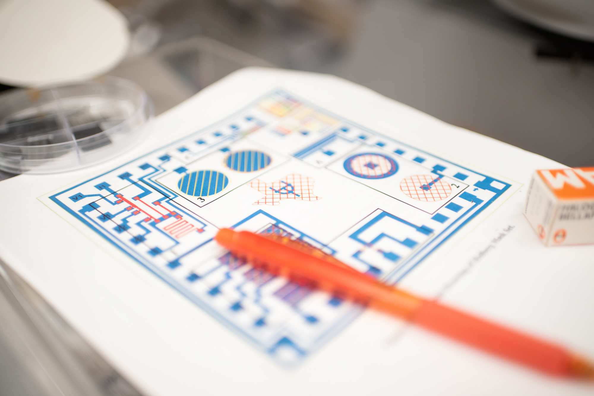 Blueprint of microchip and orange pen on desk