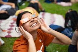 Texas Engineering student smiling and looking up while wearing eclipse glasses