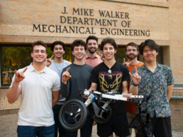 Texas Engineering students smiling with dog wheelchair prototype