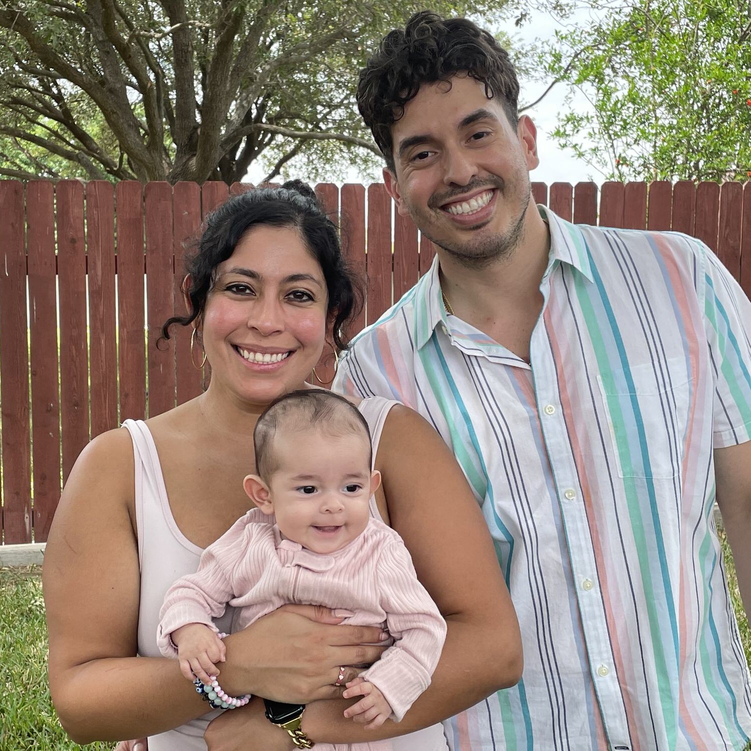Texas Engineers Anali and Julian Gonzalez smiling in a backyard holding their baby