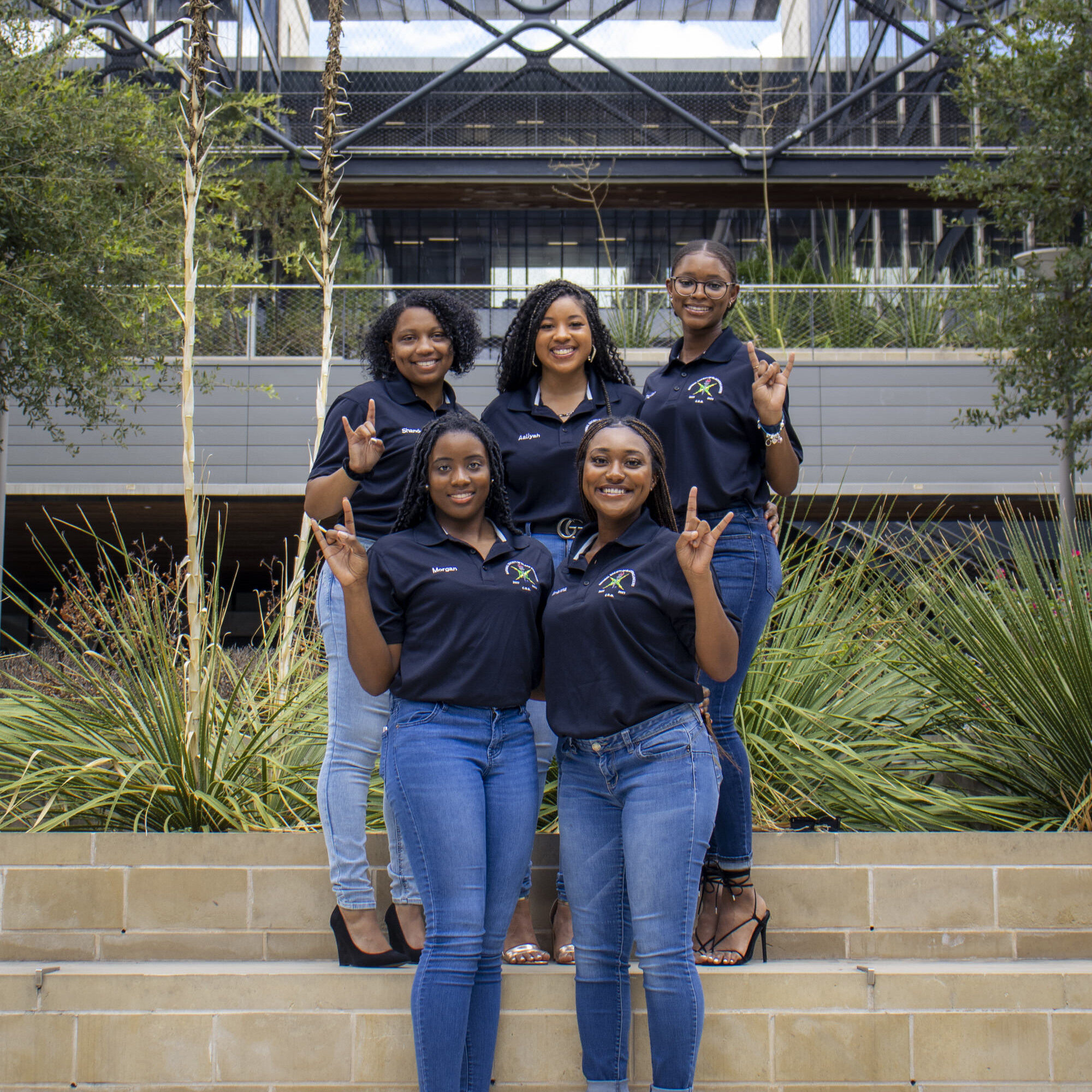 Group of NSBE student leaders smiling and doing hook 'em horns hand sign