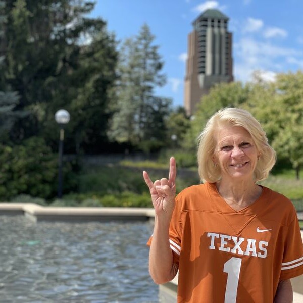 Michigan engineering Dean Karen Thole wearing UT jersey and doing hook 'em horns hand sign