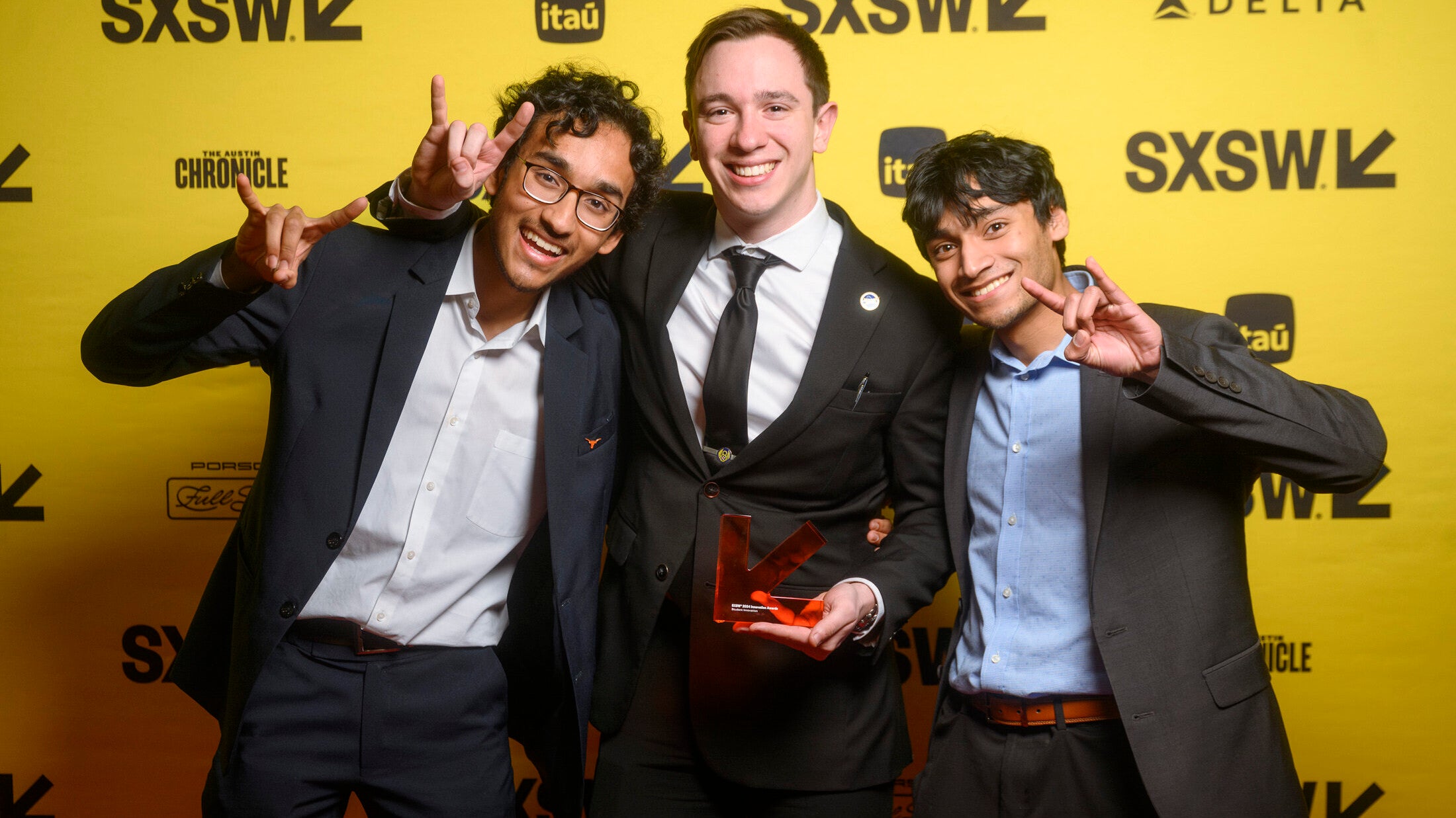 Texas Engineer Siddharth Thakur and Paradign Robotics team smiling and holding award in front of SXSW backdrop