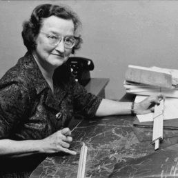 Black and white photo of Texas Engineer Leah Moncure working at desk with maps