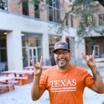 Guillermo Nieves smiling and doing hook 'em horns hand sign outside