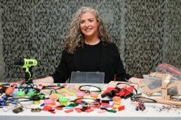 Kiersten Fernandez smiling behind table of craft supplies