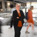 Michele Meyer stands in EER while students bustle behind her