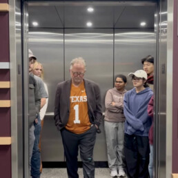 Dean Bishop stands sad in elevator with students