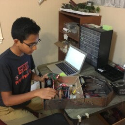 Young Siddharth Thakur in childhood home with earliest Firebot prototype.