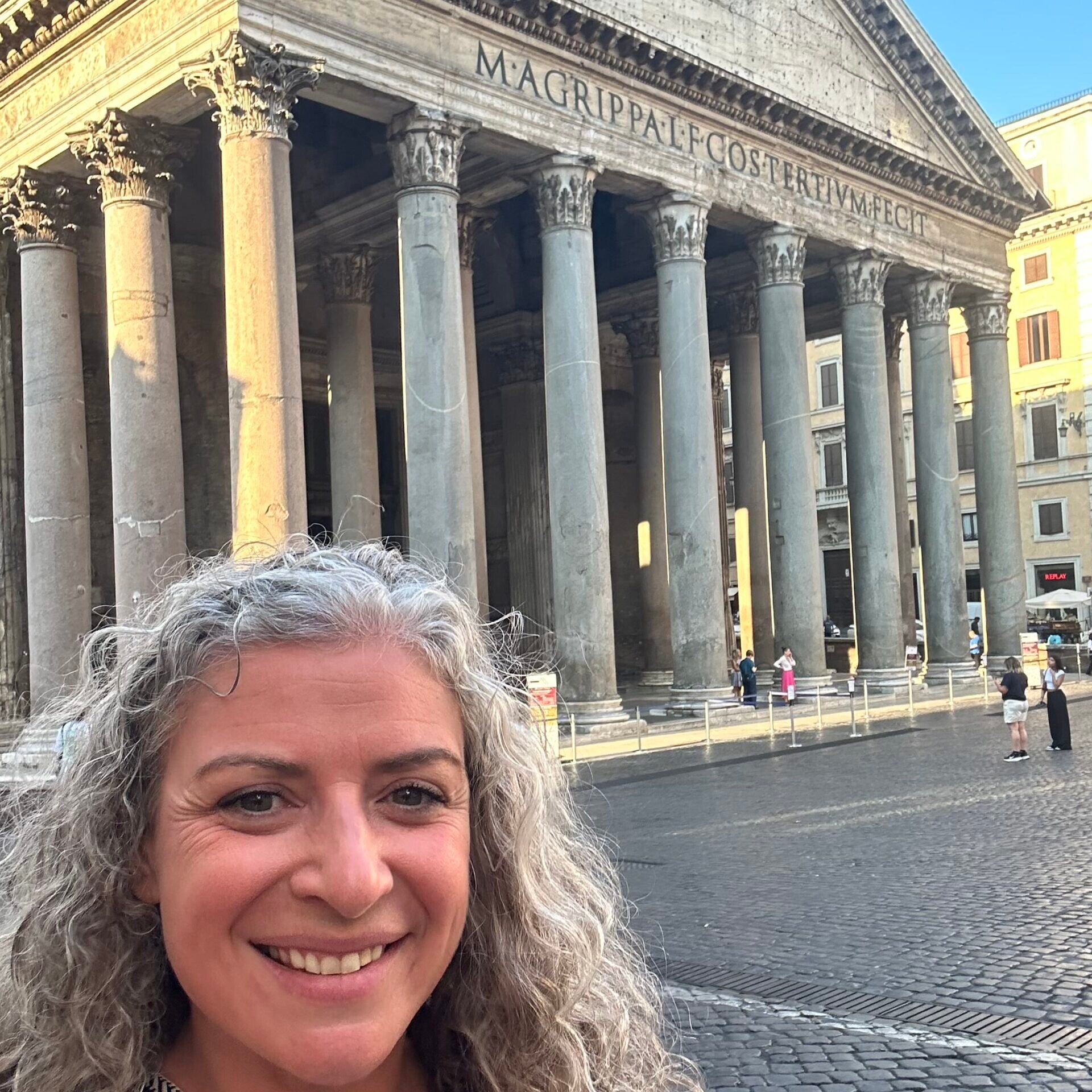 Kiersten Fernandez taking a selfie in front of historic building in Greece.