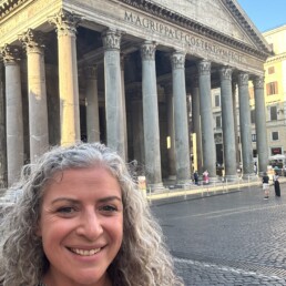 Kiersten Fernandez taking a selfie in front of historic building in Greece.