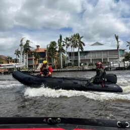 Firefighters in speedboat on the water in front of building