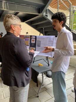 Michele Myer listens to student presenting research at Gone to Engineering event.
