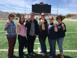 Michele Myer poses on the turf of the stadium amongst ESS staff at appreciation event.