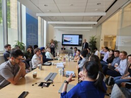 David Baldwin presenting in front of full conference room during a team meeting.