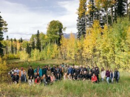 Group of people smiling in a field surrounded by trees during Open Minds meeting