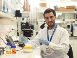 UT Portugal researcher holding samples in a lab while wearing name tag and lab safety gear